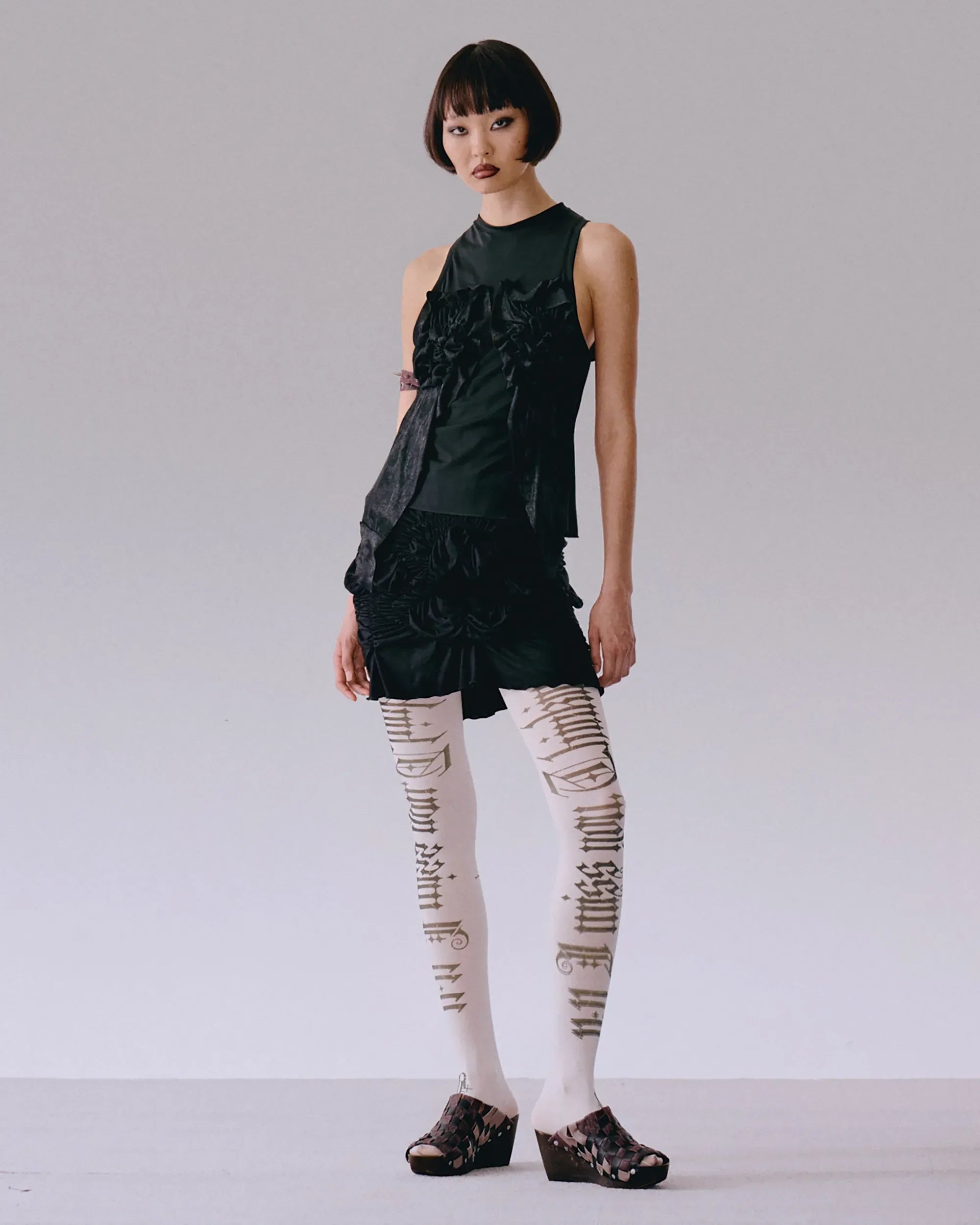 Model wearing black top with roses applique, fitted silhouette
