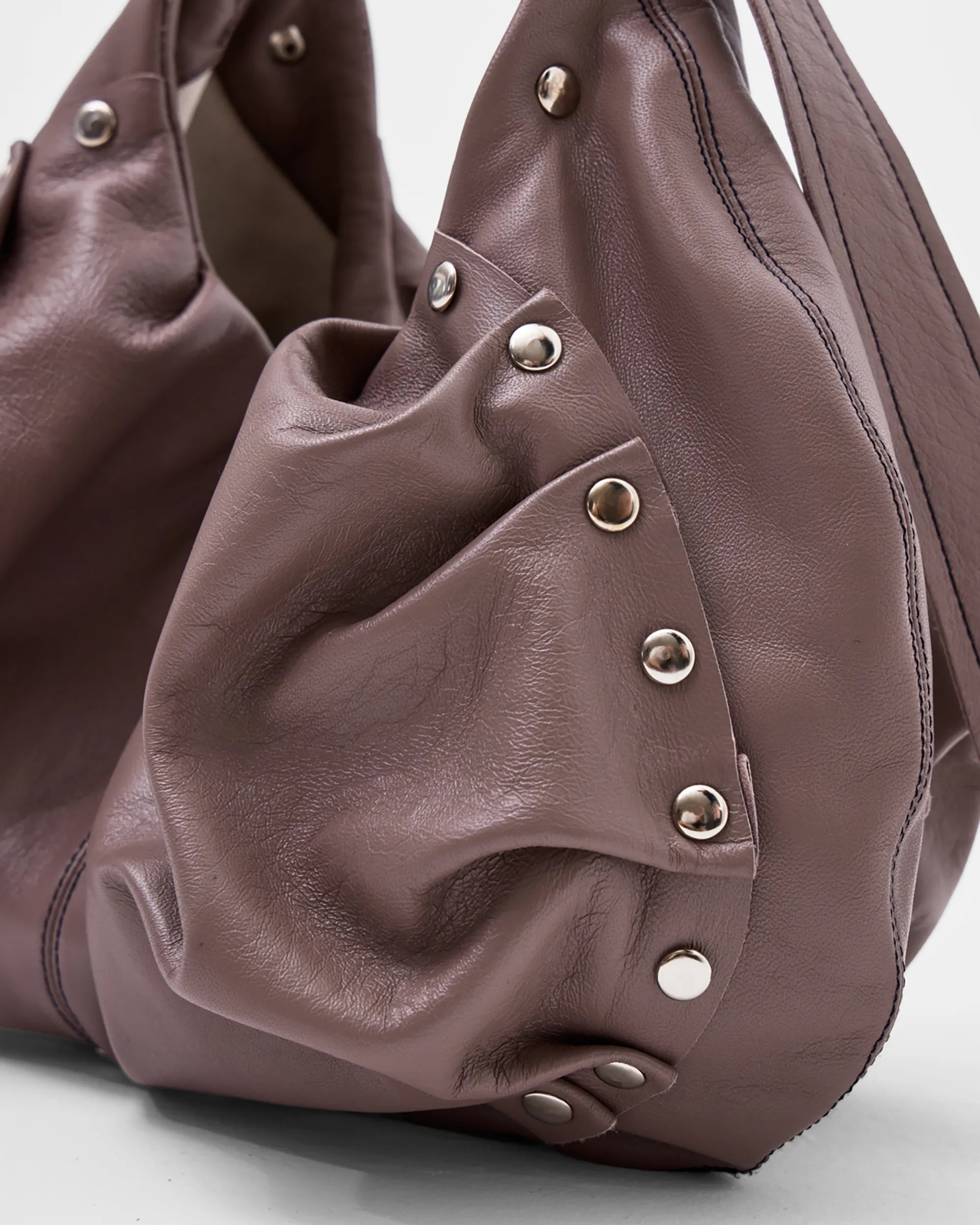 detail shoot of mauve leather shoulder bag with bespoke buckle and ruching