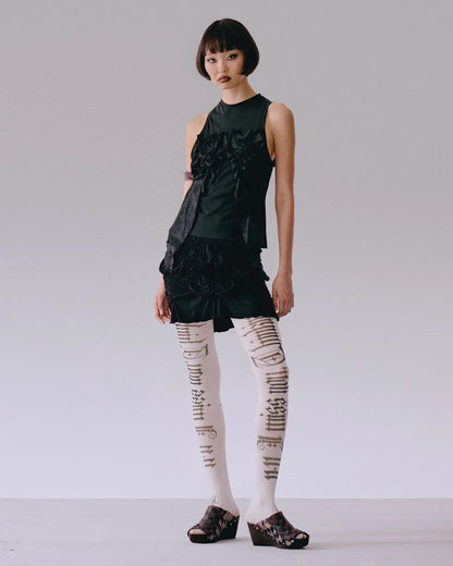 Model wearing black top with roses applique, fitted silhouette